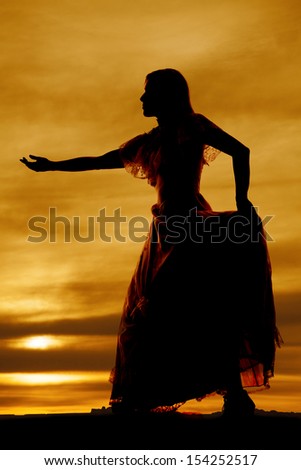 a silhouette of a woman in her dress with her hand reaching out .