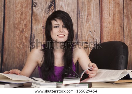 A woman with a confused expression on her face trying to study all these books.