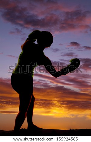 a silhouette of a woman boxing with her gloves on.