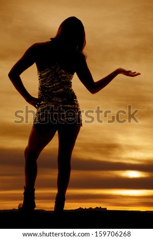 A silhouette of a woman standing up holding out her hand.