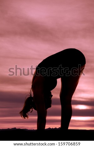 a silhouette of a woman bending over and stretching.