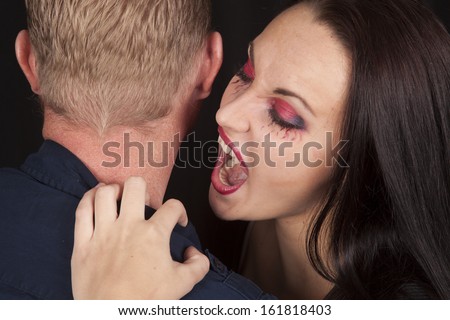 A female vampire getting ready to take a bite out of a man\'s neck.