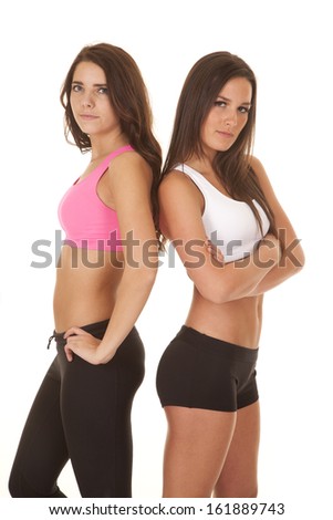 Two women are in sports bras standing back to back.