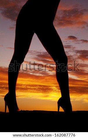 A silhouette of a woman legs in the sunset.