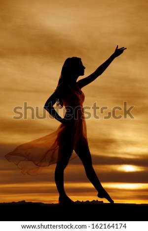 A silhouette of a woman\'s dress blowing facing sideways with her arm out.