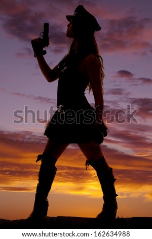A silhouette of a female cop holding her gun up.