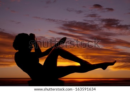 A silhouette of a woman lifting up her legs.