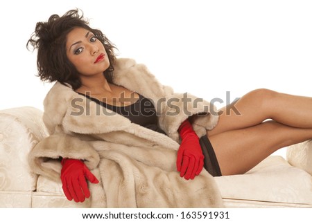 A Hispanic woman in her fur coat and red gloves, laying on a bench.