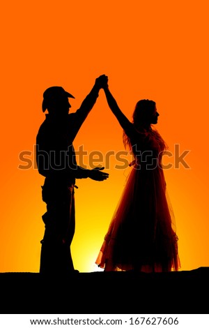 A silhouette of a man and woman dancing in the outdoors.