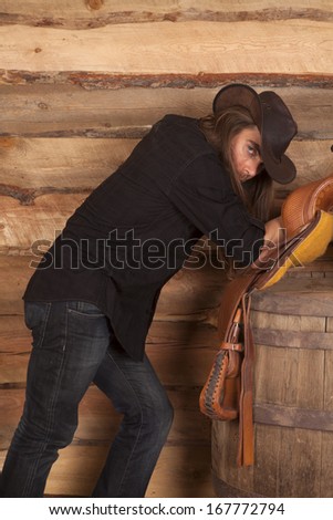 a cowboy holding on to his hat while leaning back on his saddle.