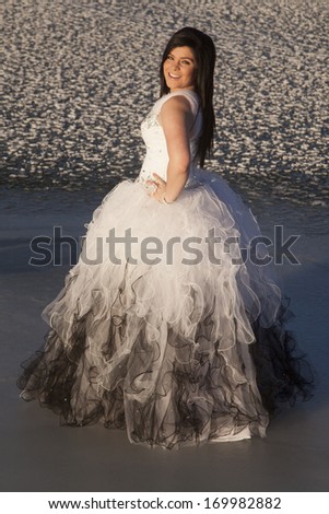 a woman in her formal dress with a smile on her face, standing on a frozen lake.