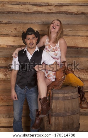 A western couple is laughing together in front of a wood background.