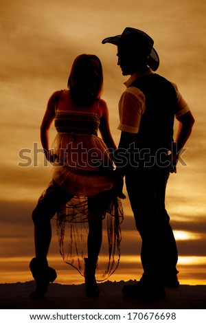 a silhouette of a woman holding up her dress looking at her cowboy.