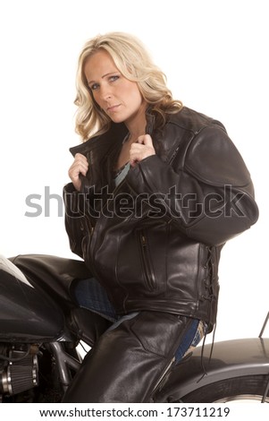 A woman on a motorcycle holding her black jacket.