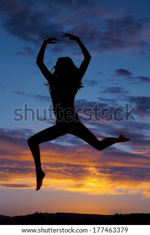 a silhouette of a woman doing a dance leap.
