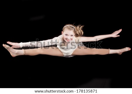 a young girl doing a toe touch in her dance outfit.