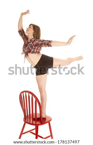 a woman doing a dance pose while standing on top of the chair in her western crop top.