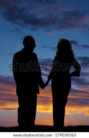 A silhouette of an older couple holding hands in the outdoors.