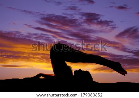 A silhouette of a woman stretching in the sunset.