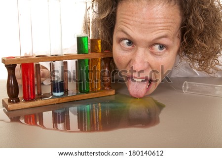 A crazy woman scientist licking up some spilled liquid.
