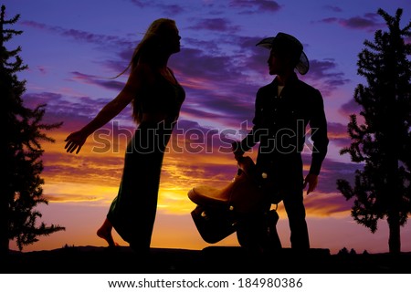 A silhouette of a western couple standing in the outdoors.