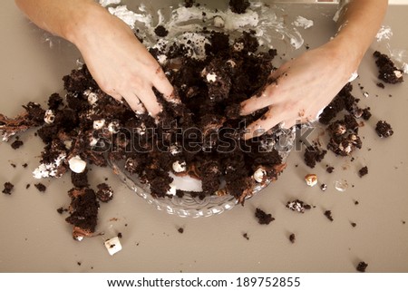 A woman\'s hands in a cake making a mess.