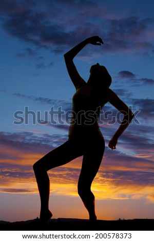 A silhouette of a woman leaning back and dancing in the outdoors.