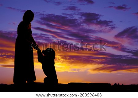 a silhouette of a woman holding on to her dogs paws