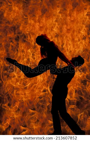 A silhouette of a man and woman dancing, he is doing a lift, with a background of fire.