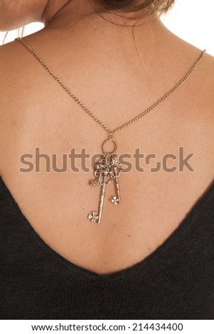 A close up of a woman\'s back wearing a necklace with key charms.