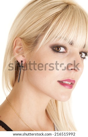 a woman\'s side of her face wearing a black cross in her ear.
