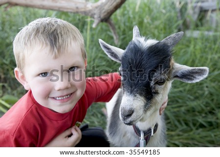 A young boy with a smile on his face, hugging his goat.