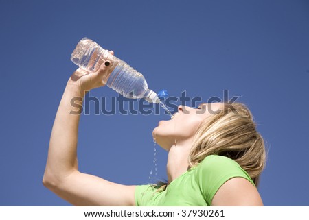 A woman thirsty for water pouring the water in her mouth.