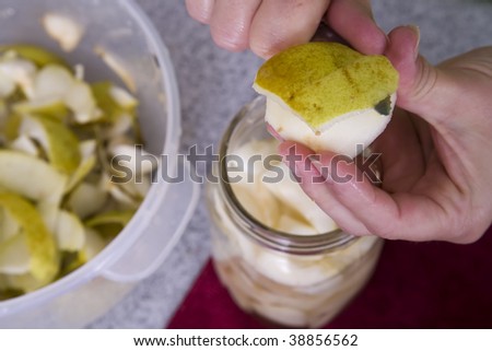 A women hands using a knife to cut the skin off a pear.