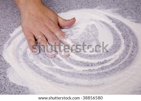 A hand mixing the flour on a counter top.