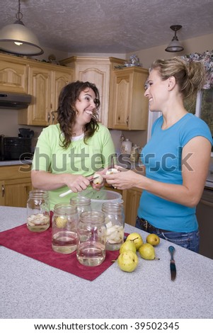 Two woman using knifes to cut the fruit to put into the bottles.