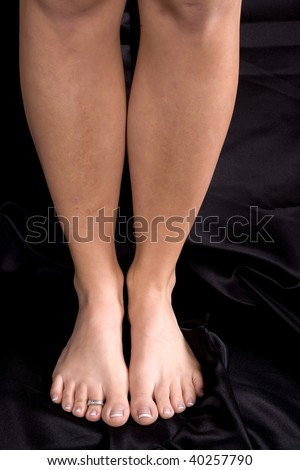 A woman standing tall with legs and feet together on black background.