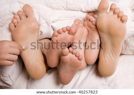A family of feet poking and getting tickled by a feather by a child.