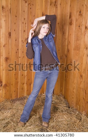 A woman standing by a wood wall with a serious look on her face with arms up.