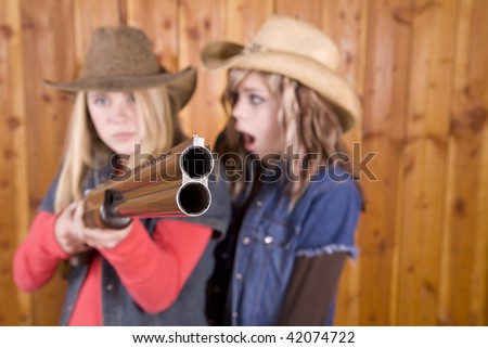 Two teen pointing a shot gun with angry expression on her face with her friend being surprised.