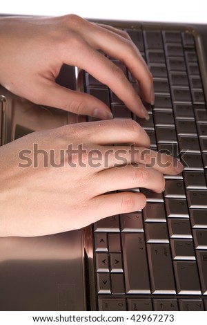 A womans hands on a keyboard of a laptop typing and working.