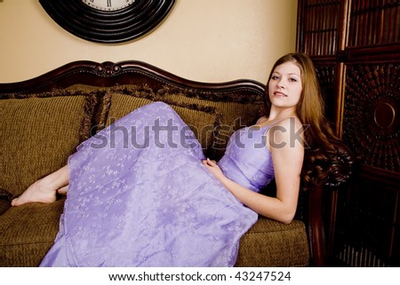 A woman laying back in her purple formal with bare feet poking out with a small smile on her face.