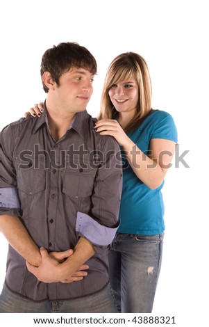 A teen boy standing with a smirk on his face while his girlfriend with small smile on her face.