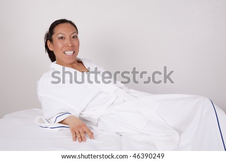 A woman in her white robe laying on the massage table getting ready for her massage at the spa.