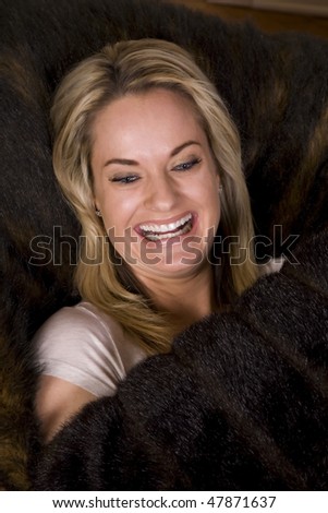 A woman relaxing holding a furry pillow with a big smile on her face.