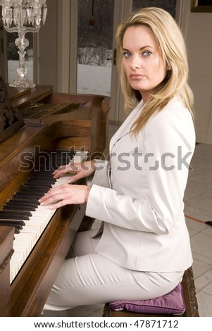 A woman sitting at the piano playing and looking with a serious expression on her face.
