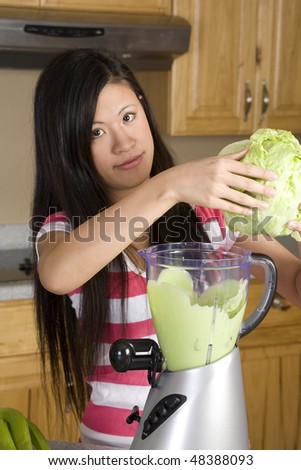 A woman adding a little lettuce into her blender to add a little fiber to her healthy smoothie.