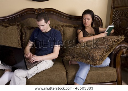 A woman looking over her man\'s shoulder to see what he is looking at on his computer.