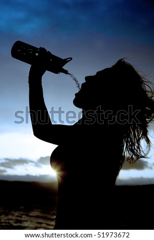 A silhouette of a woman getting refreshed by pouring water into her mouth from her water bottle