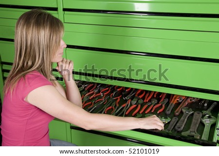 A woman looking in a tool box drawer for a pair of pliers.